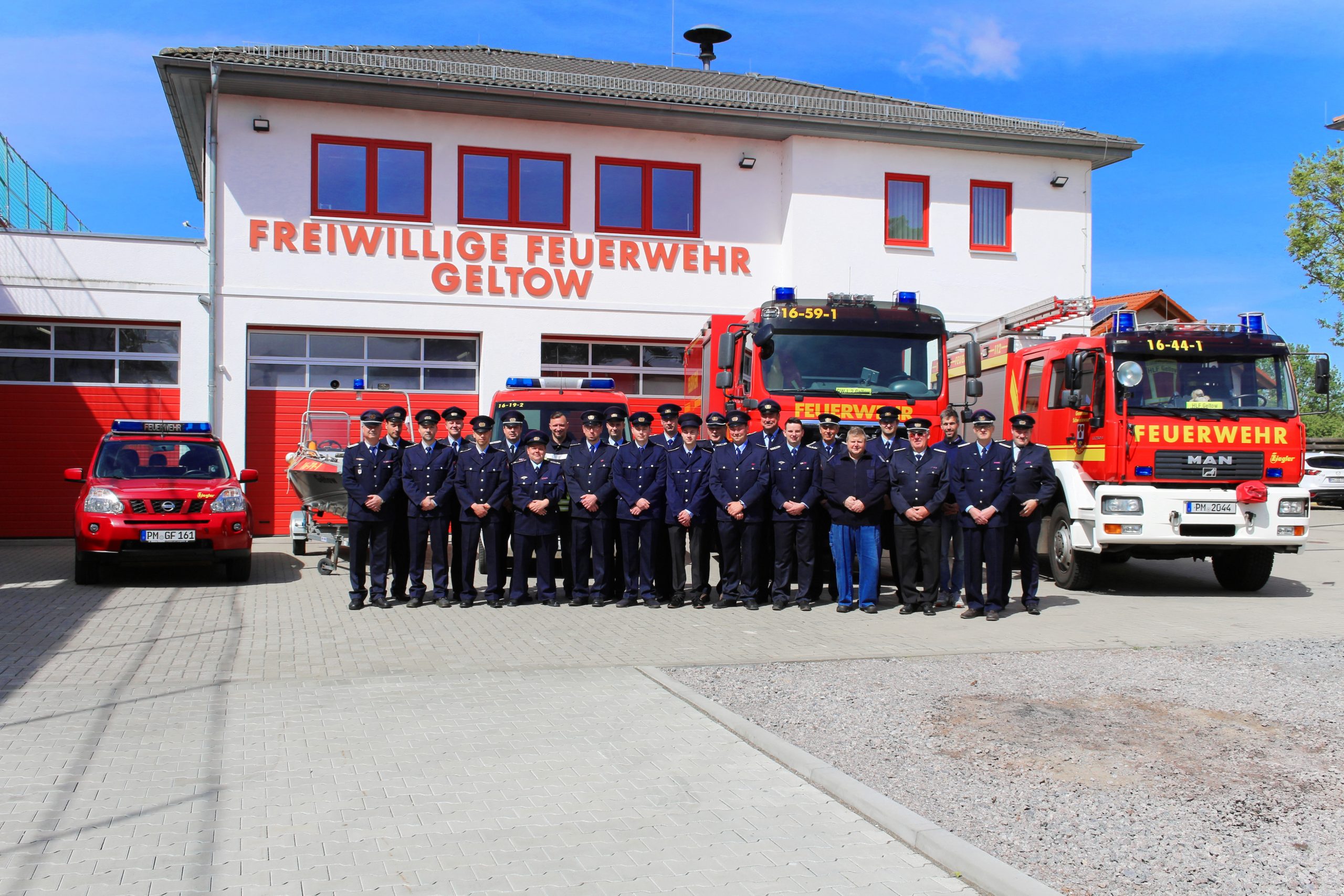 Gruppenfoto aller Kameraden der Feuerwehr, in Uniform vor den Fahrzeugen.