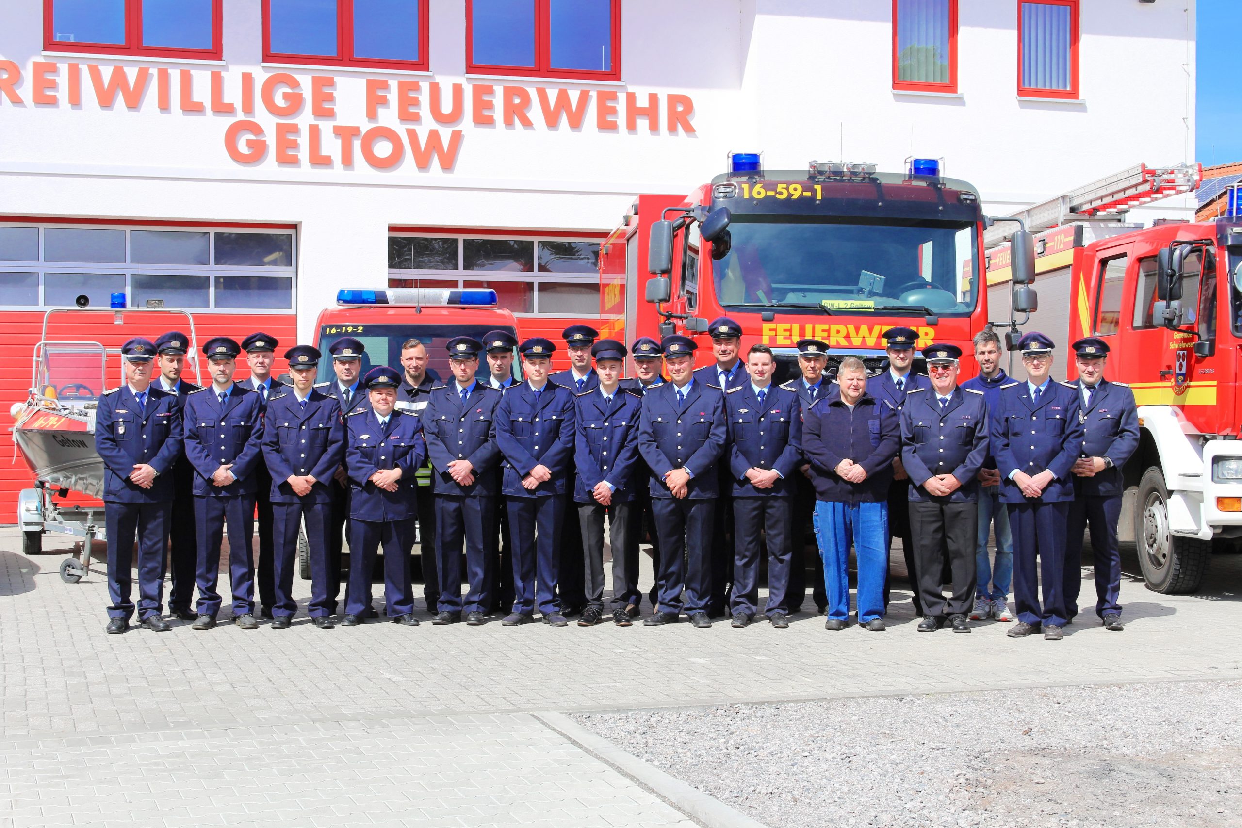Gruppenfoto aller Kameraden der Feuerwehr, in Uniform vor den Fahrzeugen.